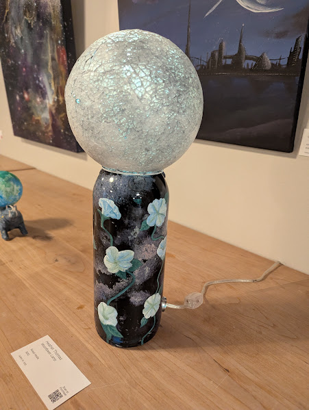 recycled glass wine bottle lamp with galaxies painted inside and moonflowers painted outside, and a round white globe top